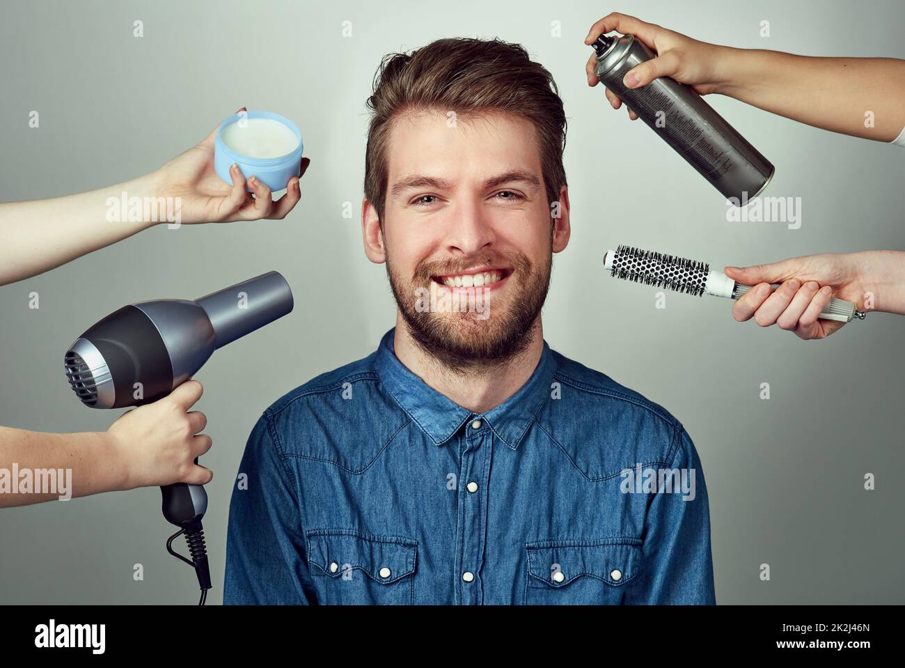 Mix up your look with a makeover. Studio portrait of a young man getting a hair makeover against a gray background. Stock Photo