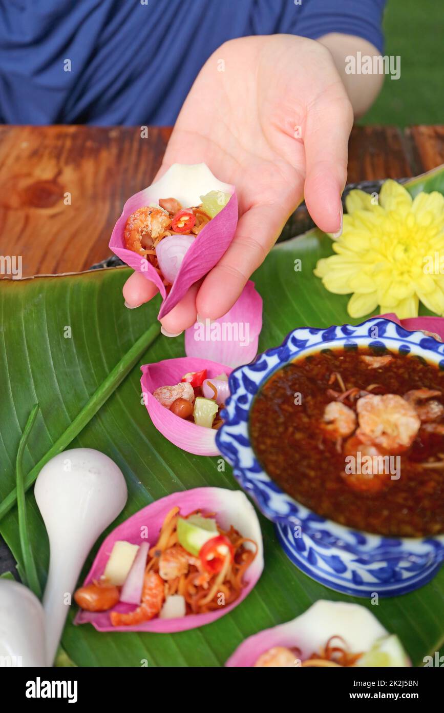Woman's Hand Holding Fresh Lotus Petal Wrapped Appetizer before Putting Spicy Dip Stock Photo