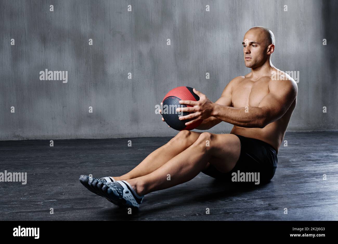 Stepping up his fitness routine. Shot of a man doing exercises with a medicine ball at the gym. Stock Photo