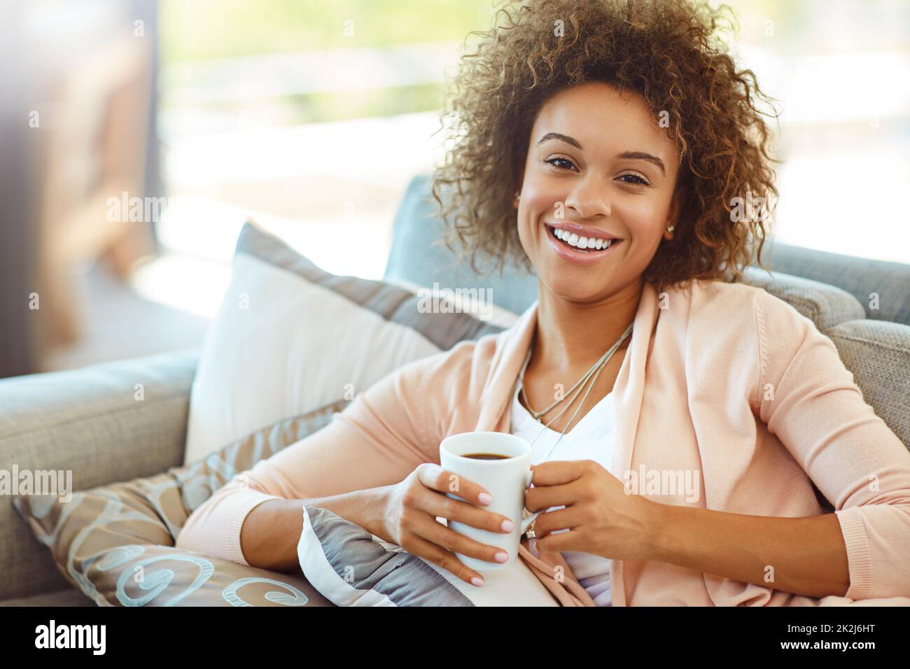 Tea time is me time. Portrait of a young woman relaxing with a warm beverage at home. Stock Photo