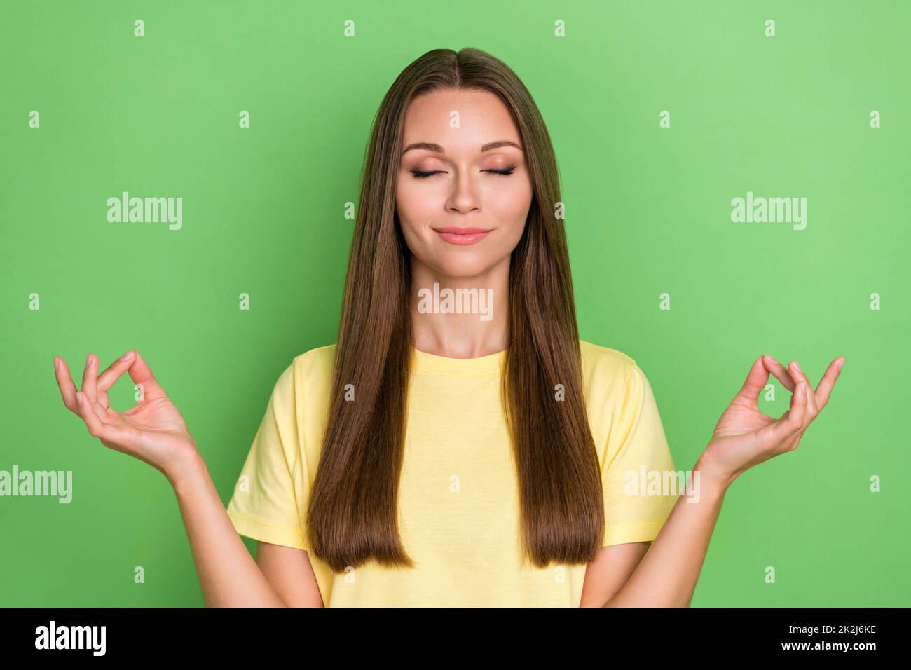 Photo of nice adorable lovely girl with straight hairdo dressed yellow t-shirt concentrated meditating relaxing on green color background Stock Photo