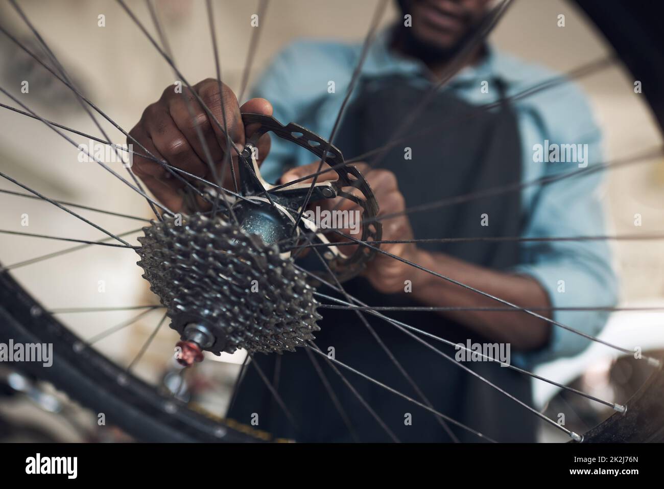 Youre almost ready for another generation of memories. Low angle shot of an unrecognizable man standing alone in his shop and repairing a bicycle wheel. Stock Photo