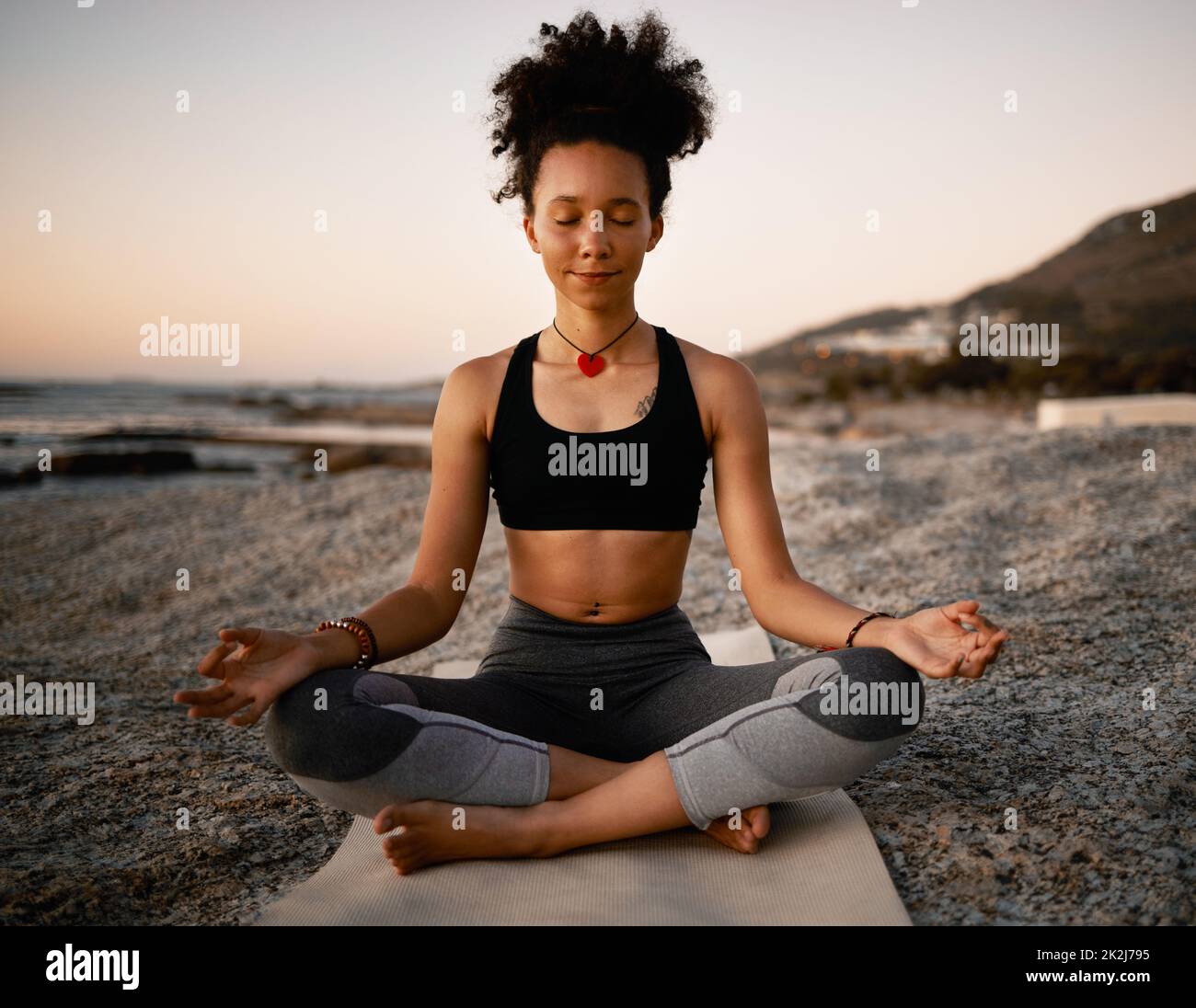 Ultimate zen. Full length shot of an attractive young woman practicing yoga on the beach at sunset. Stock Photo