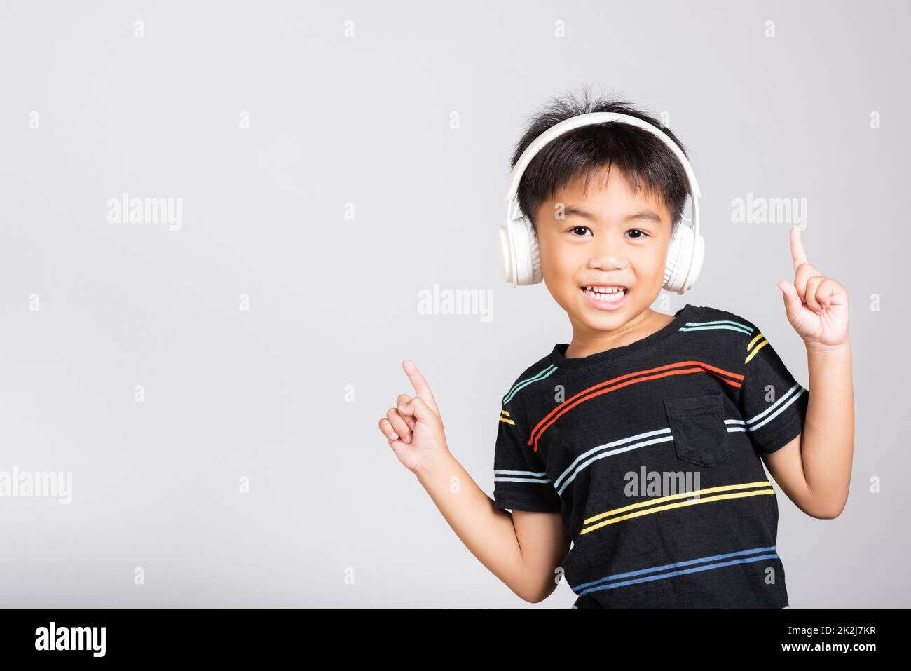 Little cute kid boy 5-6 years old listen music in wireless headphones Stock Photo