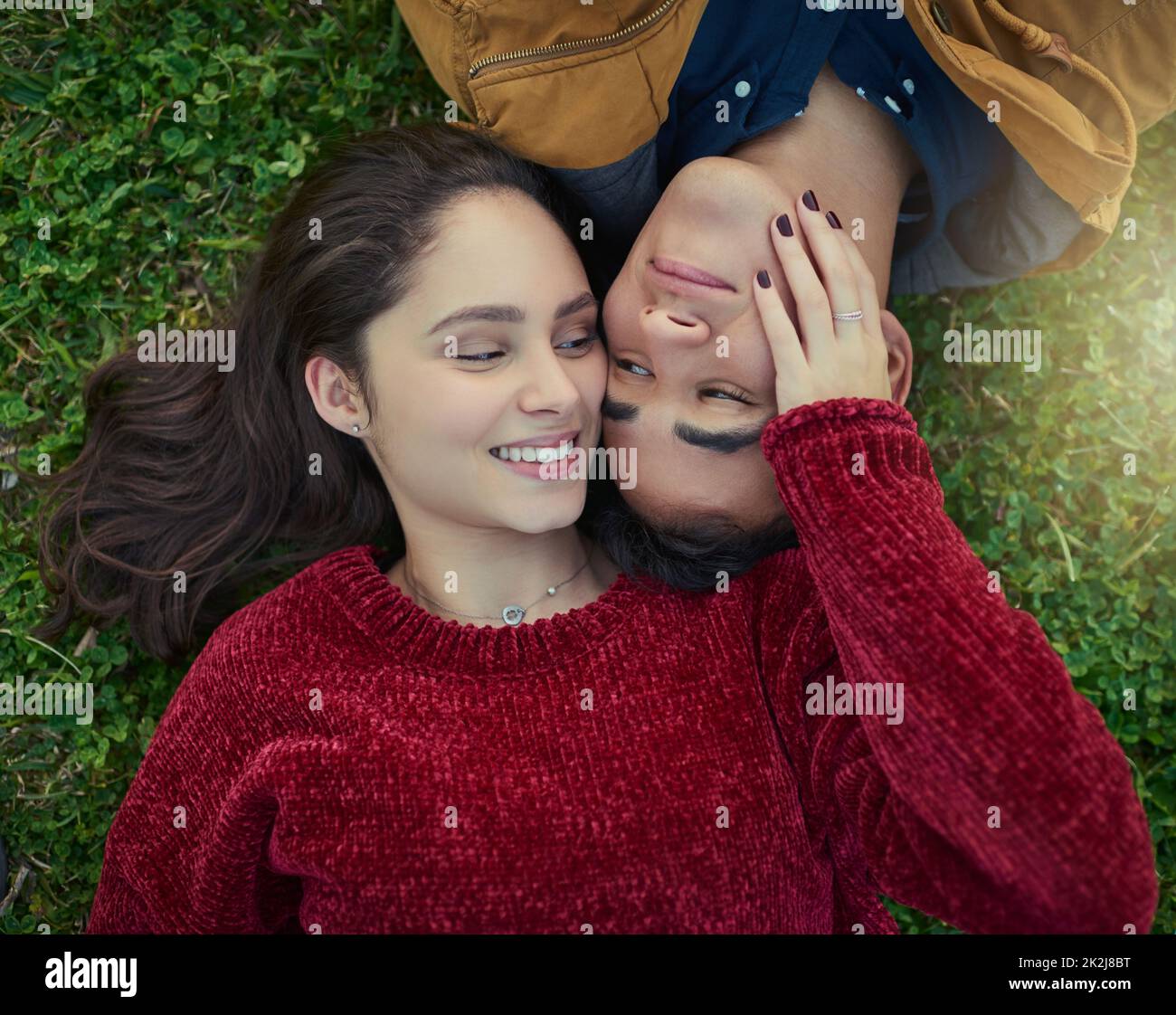 With you next to me, life is complete. High angle shot of a happy young couple laying together on the grass. Stock Photo