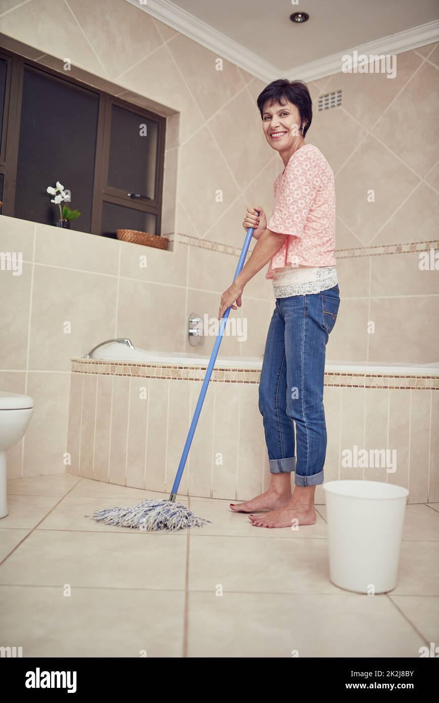 Beating the grime and dirt. Portrait of a woman mopping a bathroom