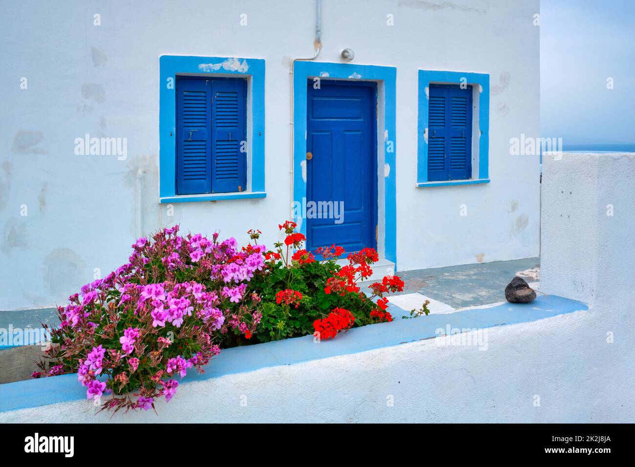 Greek white house with blue door and window blinds Oia village on