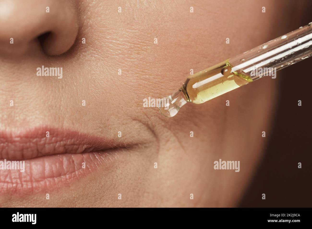 Female face and dropper with rejuvenating serum Stock Photo