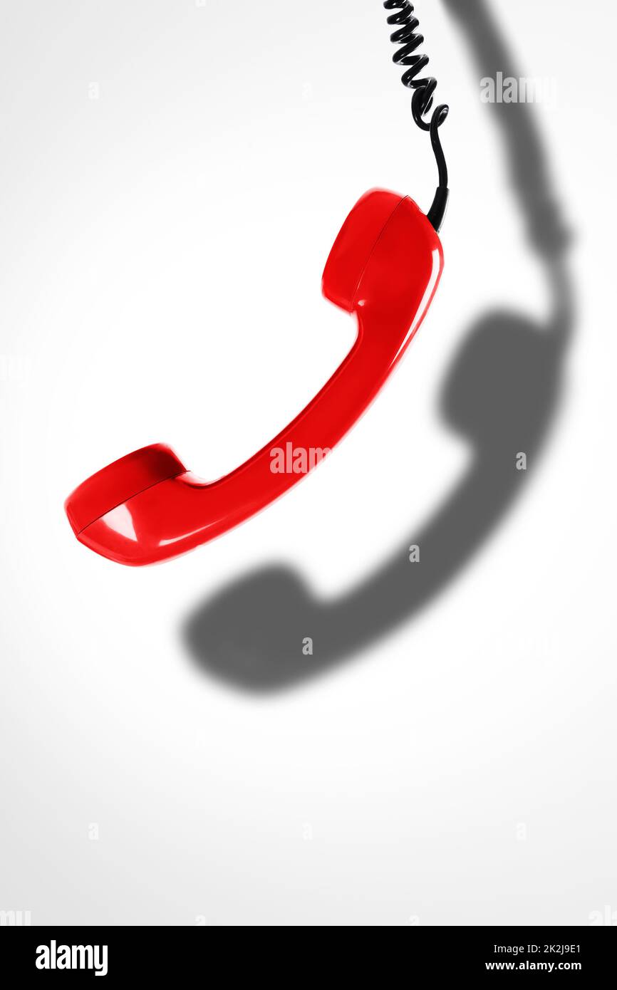 Red telephone handset with a dark shadow. Concepts of hotline, support or phone scams. Stock Photo