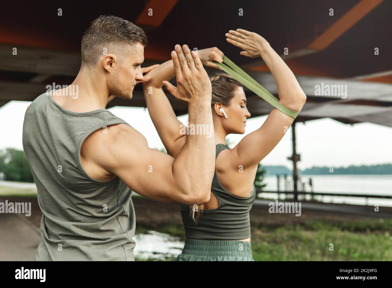 Woman during workout with a personal fitness instructor using rubber resistance bands outdoors Stock Photo