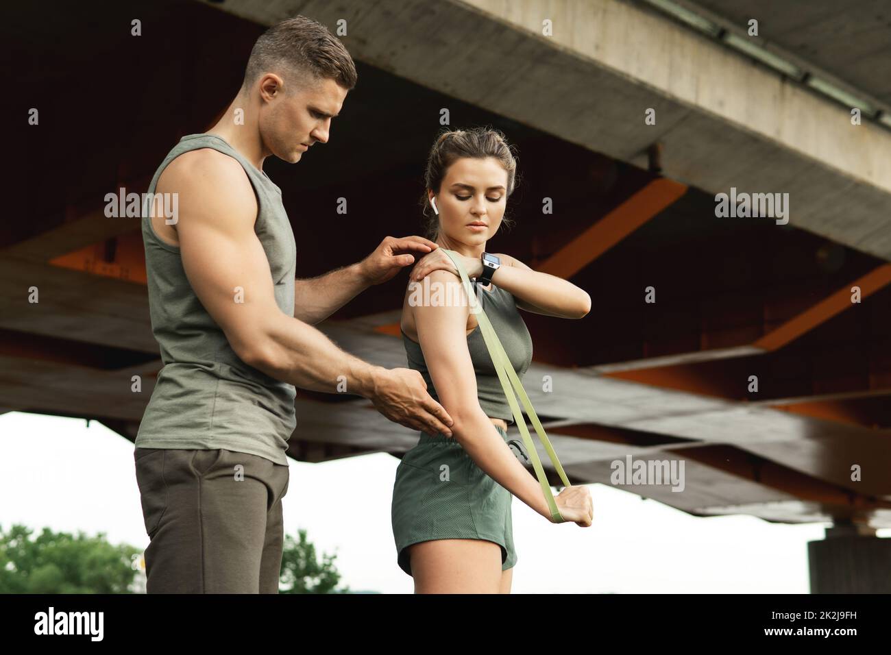 Woman during workout with a personal fitness instructor using rubber resistance bands outdoors Stock Photo