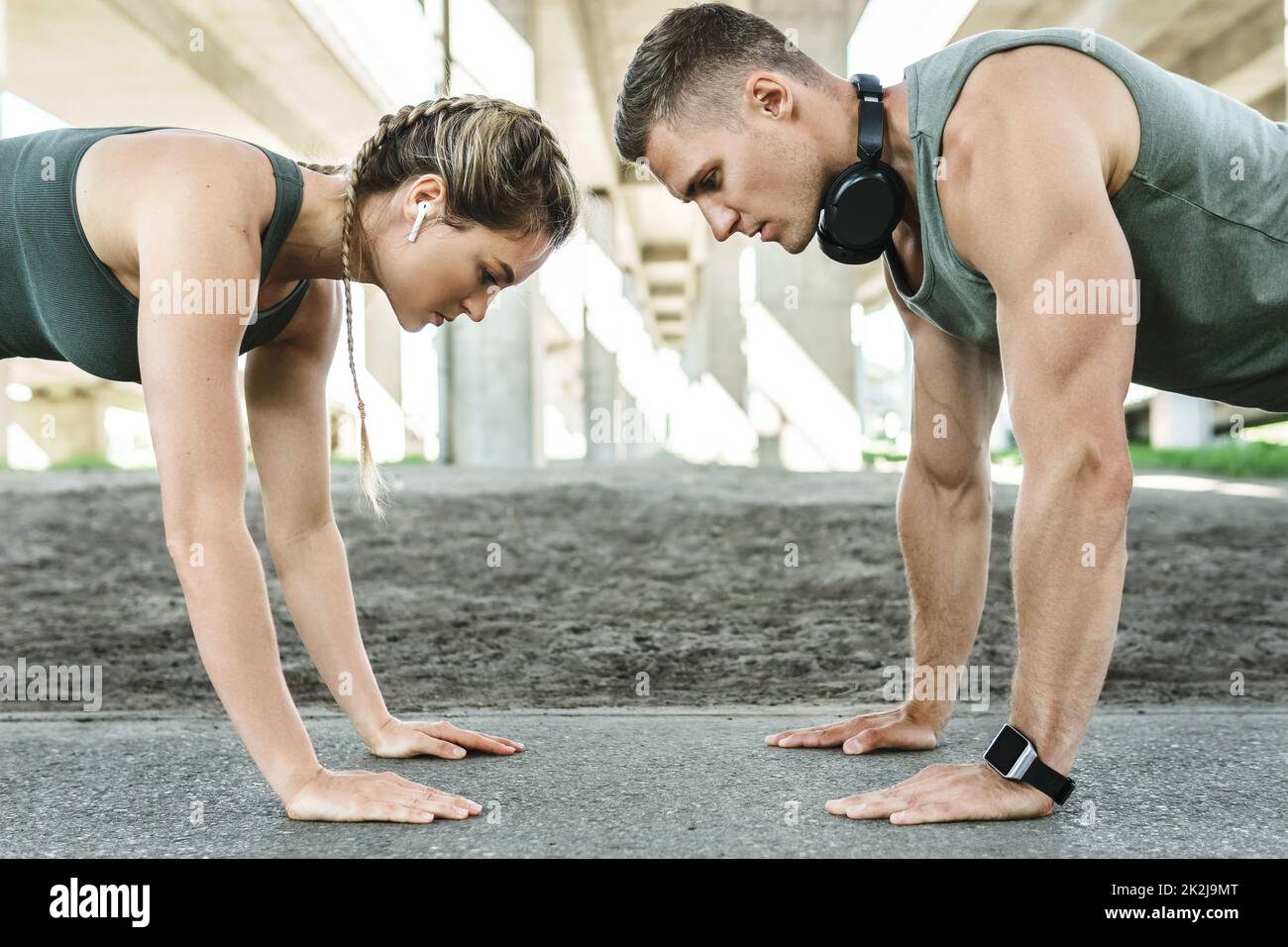Athletic couple and fitness training outdoors. Man and woman doing push-ups exercise. Stock Photo