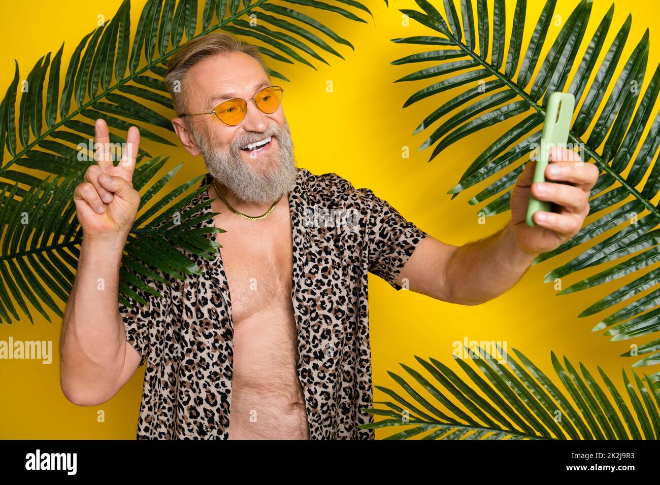 Photo portrait of attractive granddad take selfie video recording dressed stylish leopard print outfit isolated on yellow color background Stock Photo