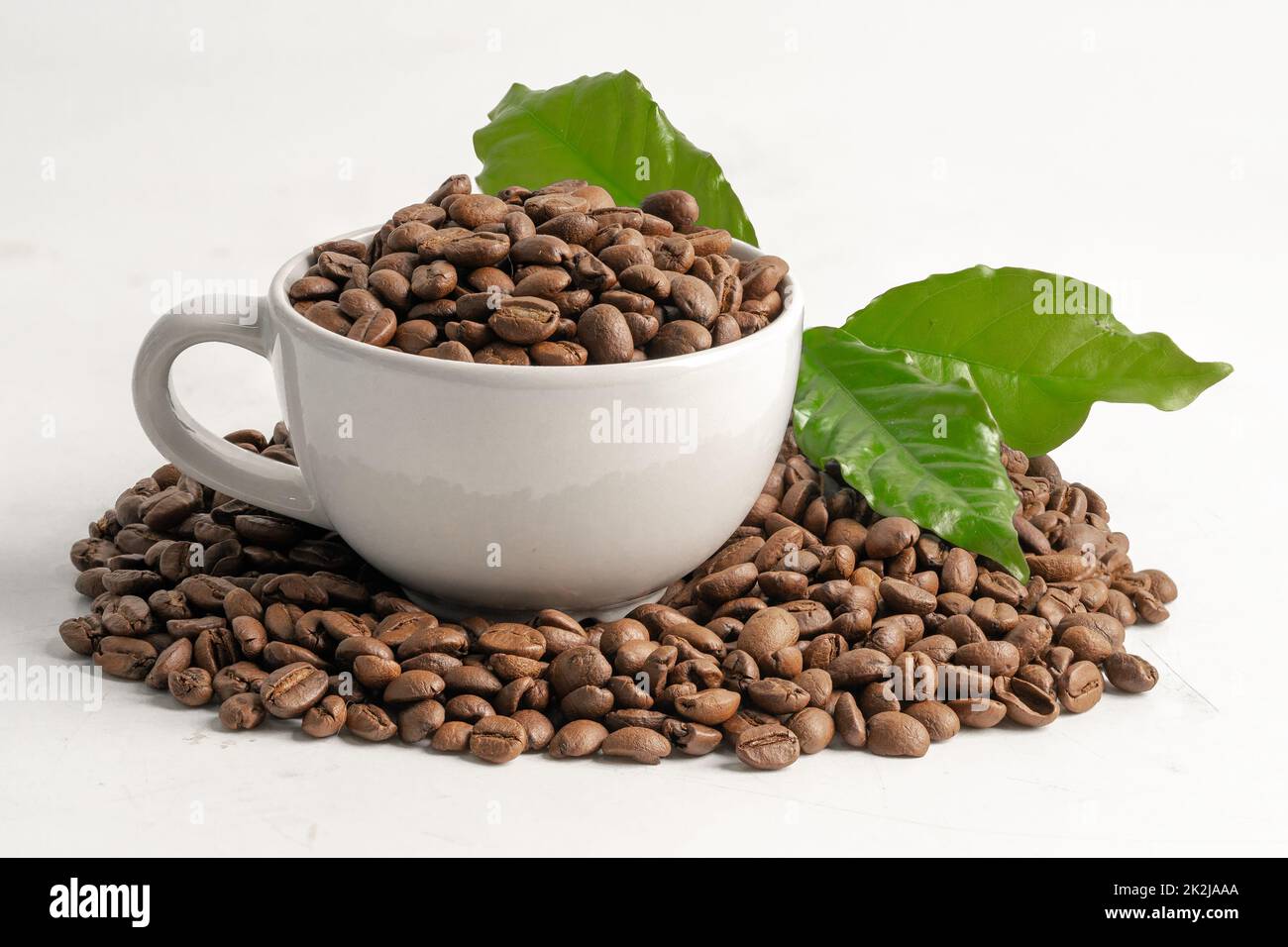Coffee bean medium roasted in cup with leaf in fresh morning isolated on white background. Stock Photo