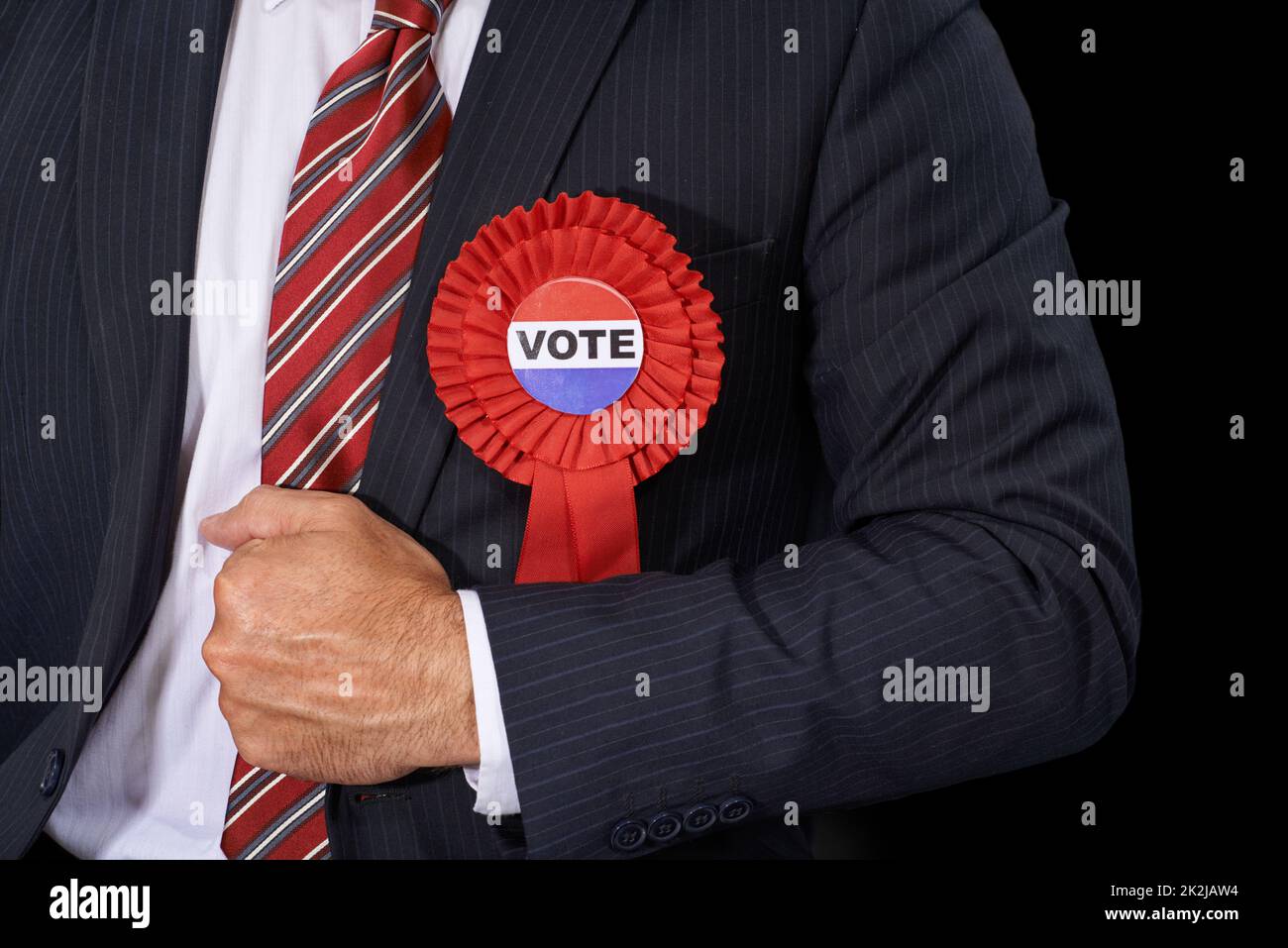 Use your votes wisely. Cropped view of a man in a suit wearing a voting ribbon ona black background. Stock Photo