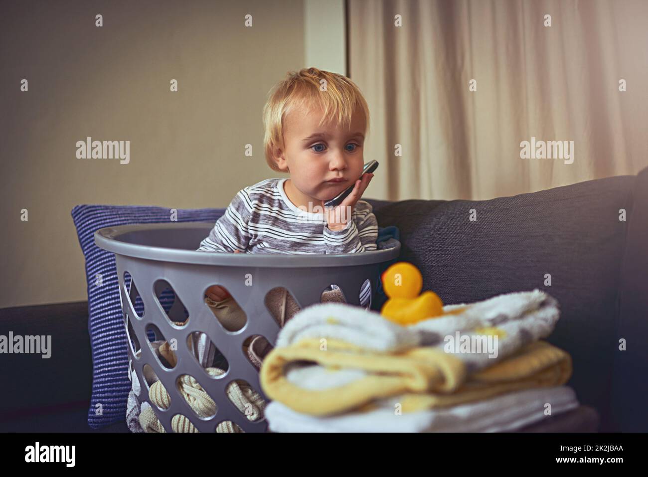Wheres the fun in doing laundry. Shot of an adorable little boy sitting