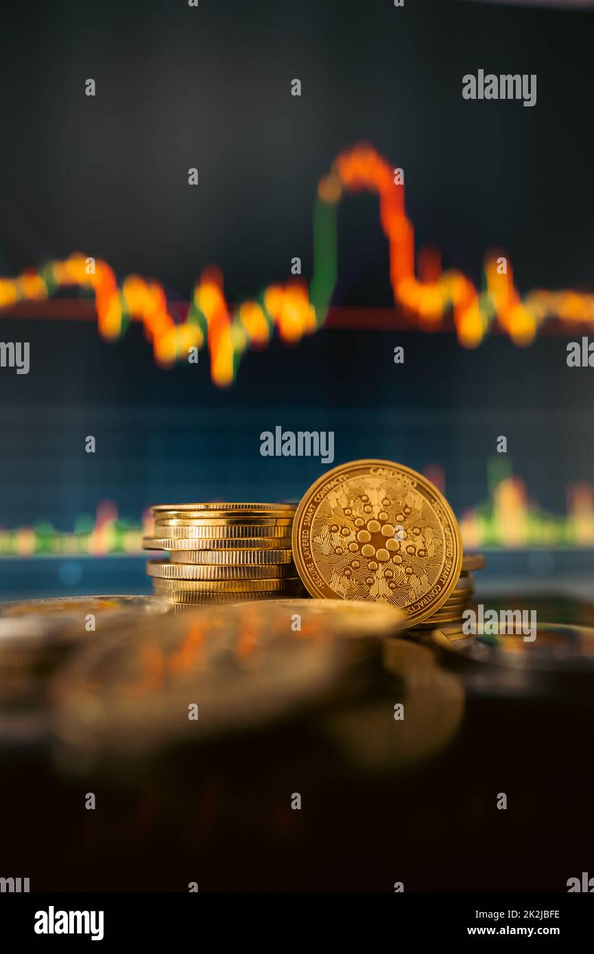 Stack or heap of gold IOTA (MIOTA) cryptocurrency with candle stick graph chart and digital background. Stock Photo