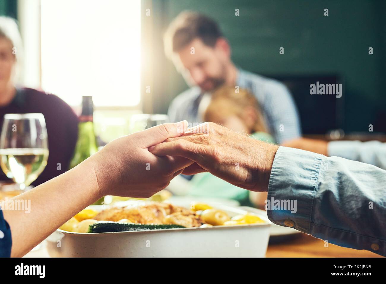 Everyone join your hands. Closeup of a peaceful family holding hands to say grace together around a dinner table at home. Stock Photo