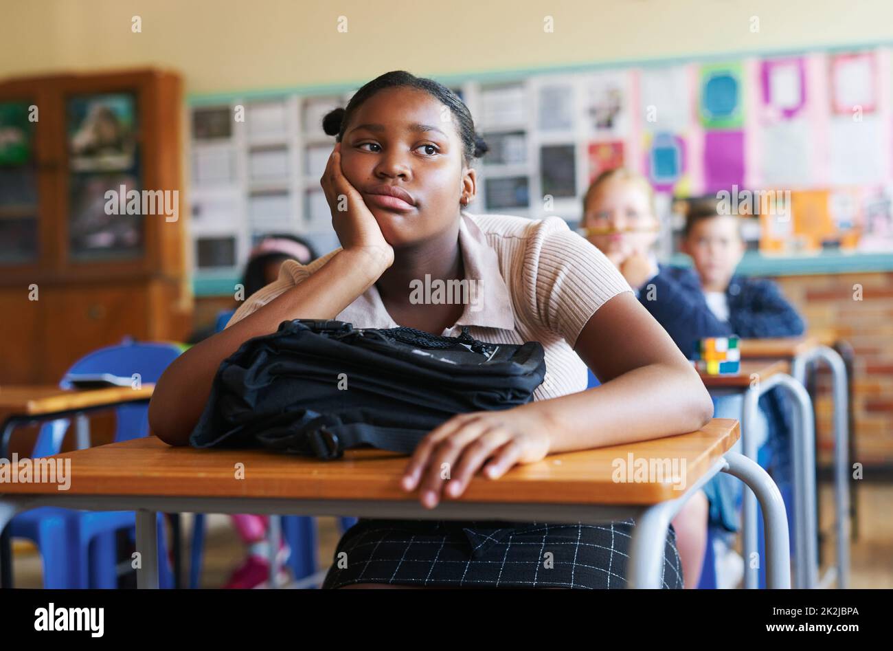 Argh, its going to be a long day. Shot of a young girl sitting in her classroom at school and feeling bored. Stock Photo