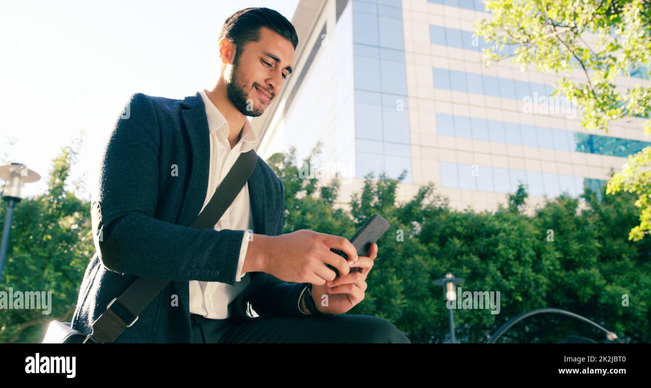 Ill be there shortly. Shot of a handsome young businessman using his cellphone while commuting to work on his bicycle. Stock Photo