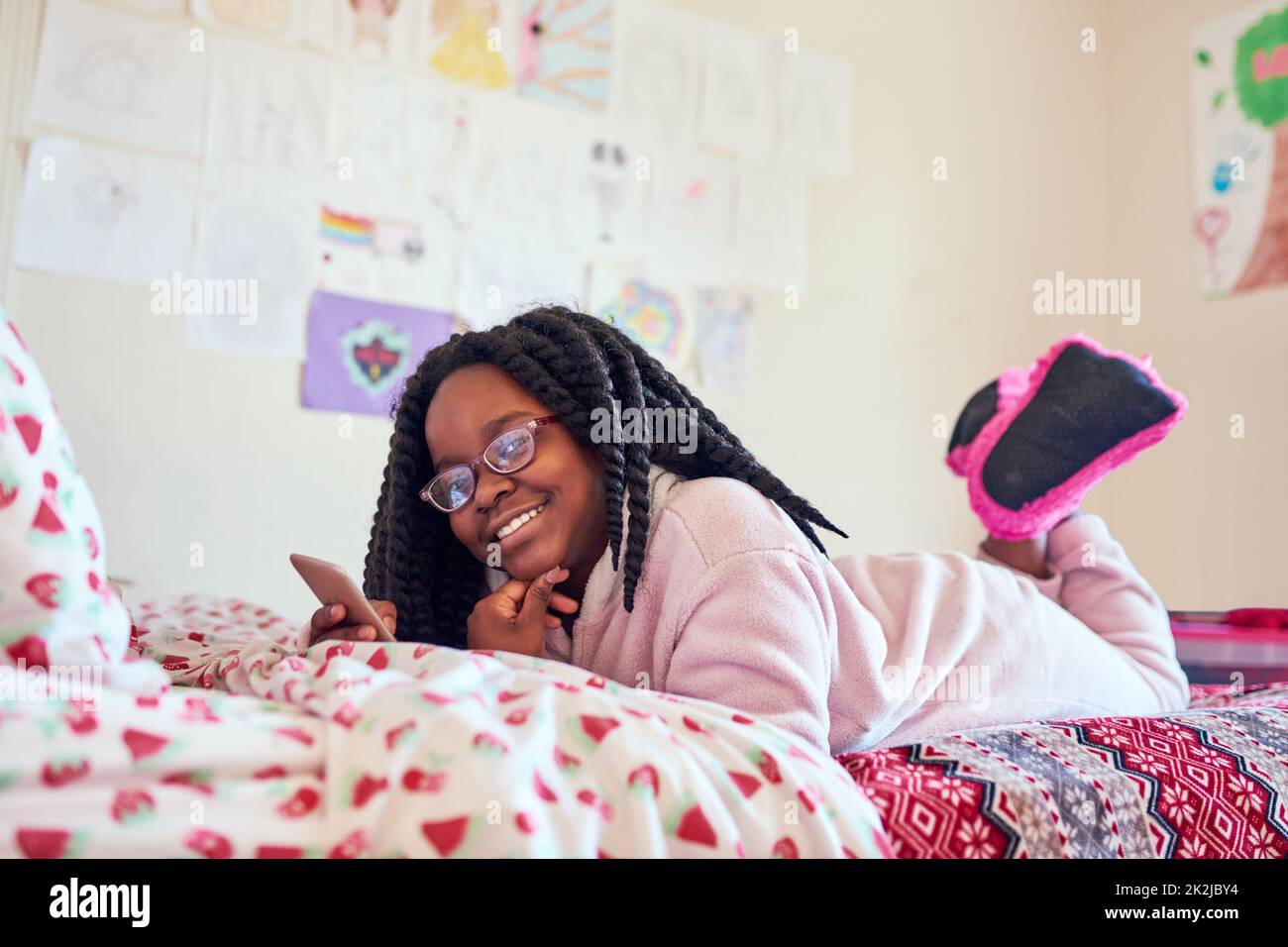 Early morning social networking. Shot of an adorable little girl using a cellphone on her bed in her bedroom. Stock Photo