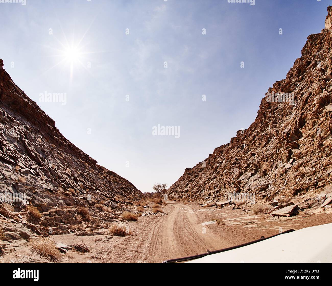Just you and the open road. Shot of a dirt road running through rugged terrain. Stock Photo
