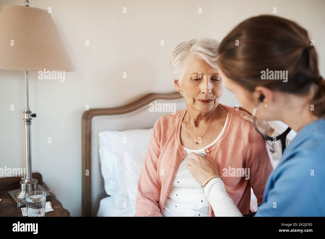 Lets see what your heart has to say. Shot of a senior woman getting a checkup from a young nurse in a retirement home. Stock Photo