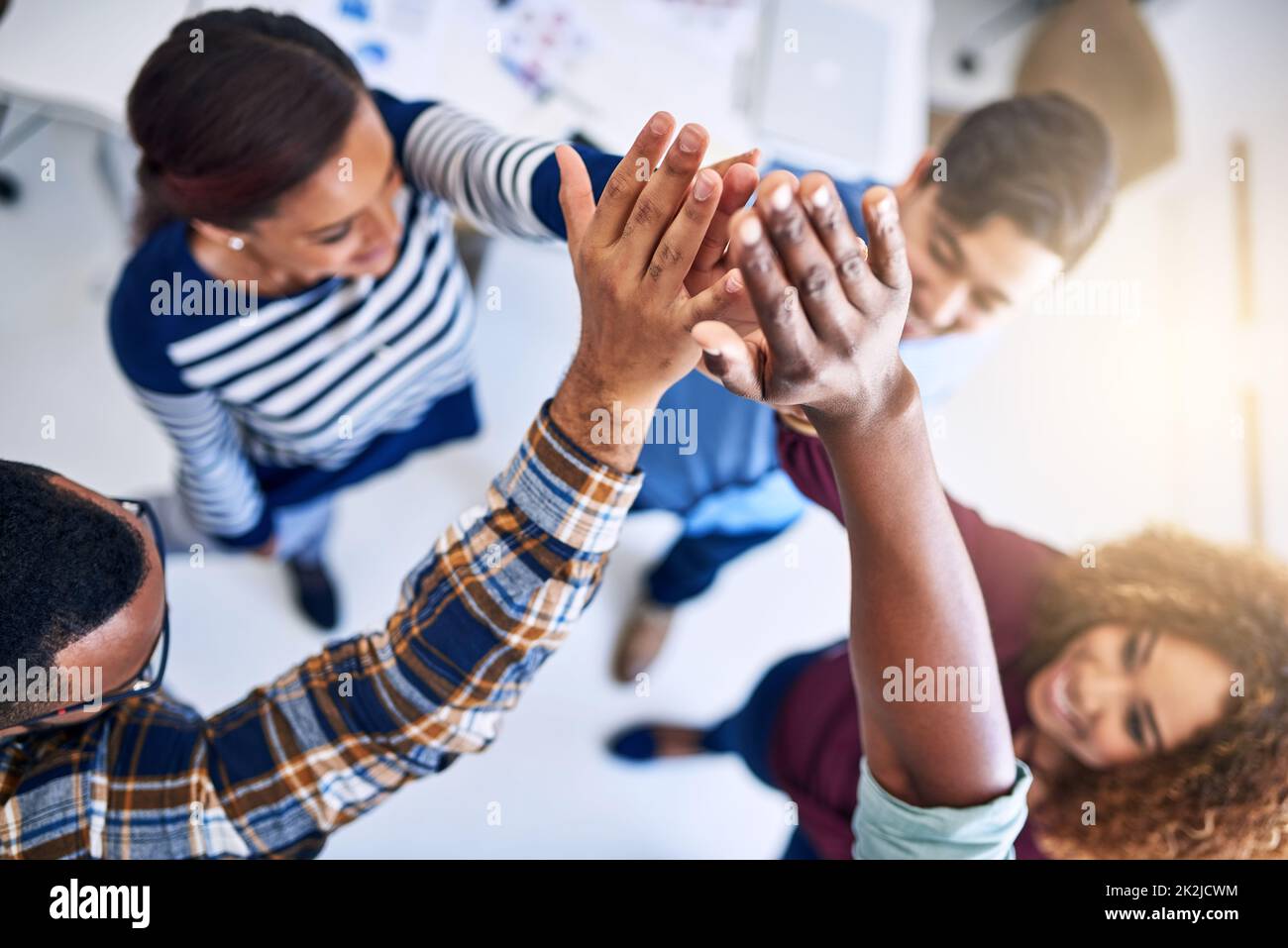 We can do this. High angle shot of a team of designers high fiving together in an office. Stock Photo