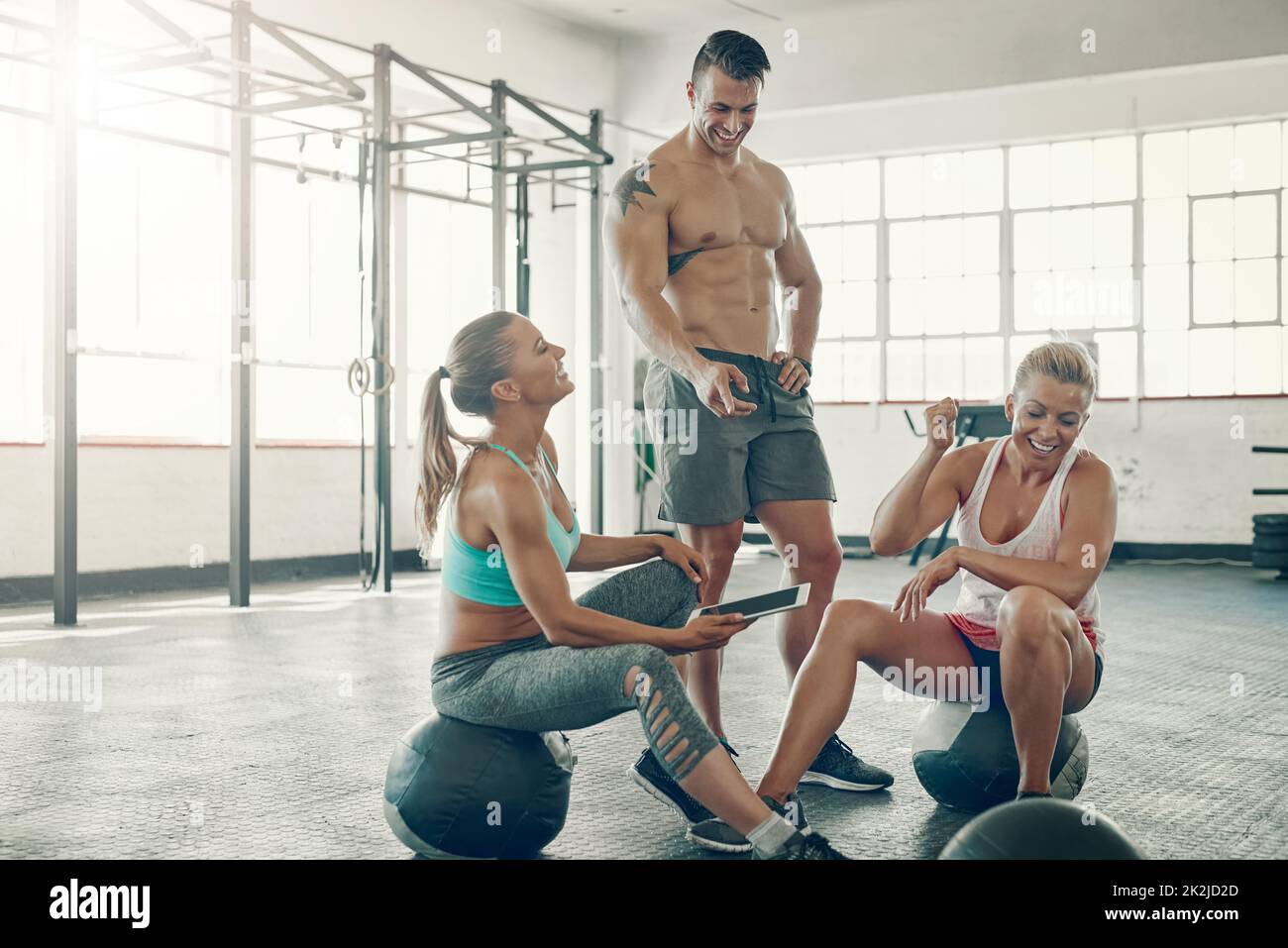 Checking out whats new on their favourite fitness blogs. Shot of a group of young people using a digital tablet at the gym. Stock Photo