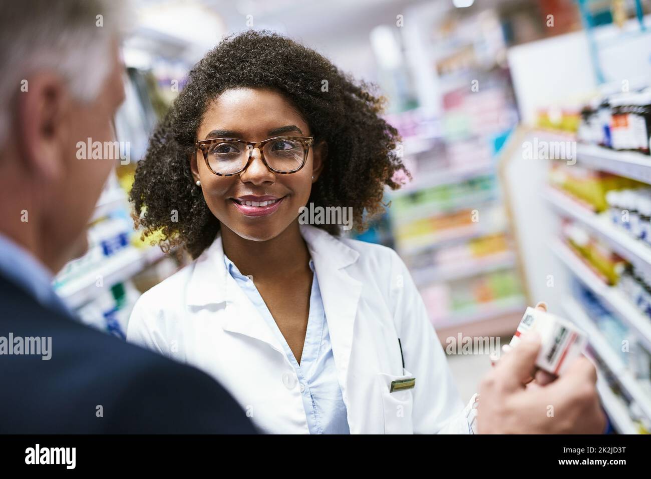 Ill take one thank you. Shot of a helpful young female pharmacist helping a customer with choosing the right medication in the pharmacy. Stock Photo