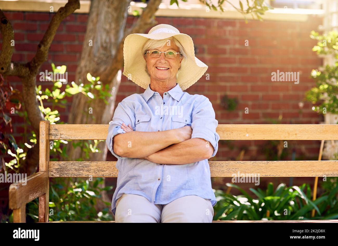 Being in the garden puts a smile on my face. Portrait of a happy senior woman relaxing on a bench in the garden. Stock Photo