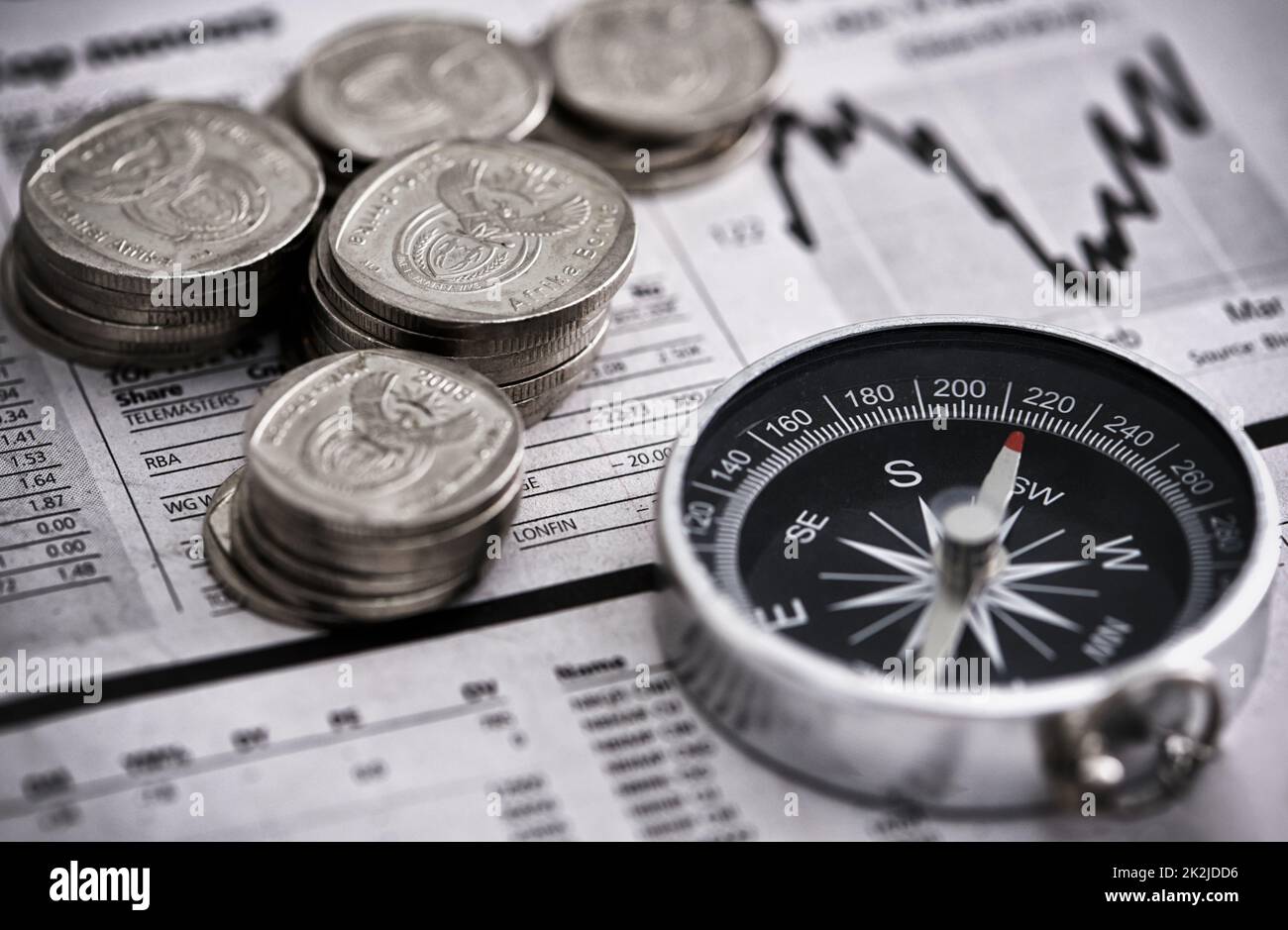 Leading the way to financial success. Studio shot of coins and a compass on the business section of a newspaper. Stock Photo