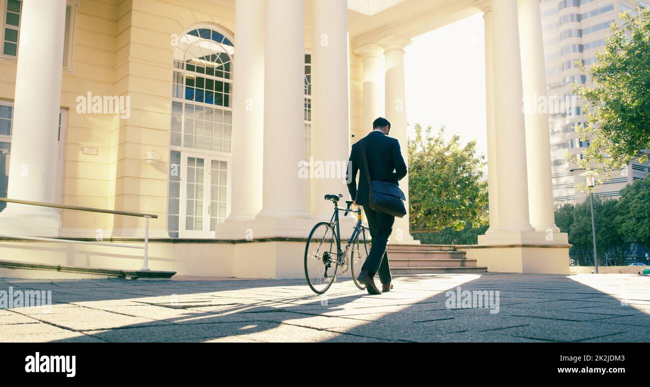Back to the 9 to 5 hustle. Rearview shot of a businessman commuting to work with his bicycle. Stock Photo