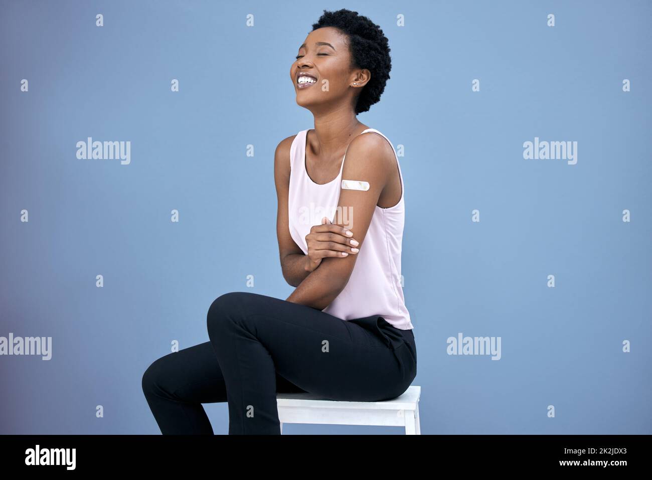 Vaccinated and happy. Shot of an attractive young woman sitting alone in the studio after getting her Covid vaccine. Stock Photo