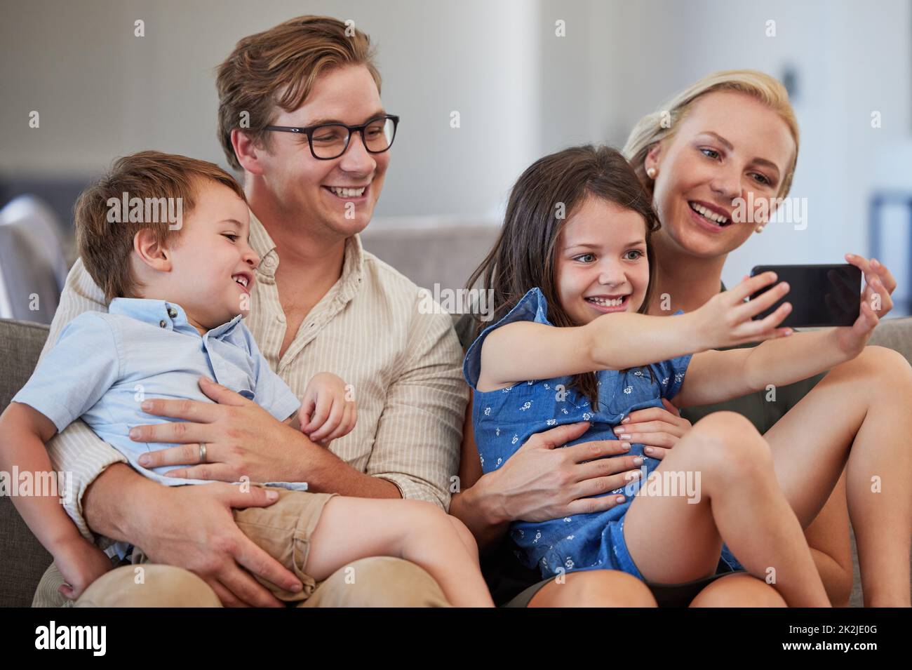 Family selfie, live streaming phone and girl on the internet with technology, smile for mobile app and record video for web on the sofa in living room Stock Photo