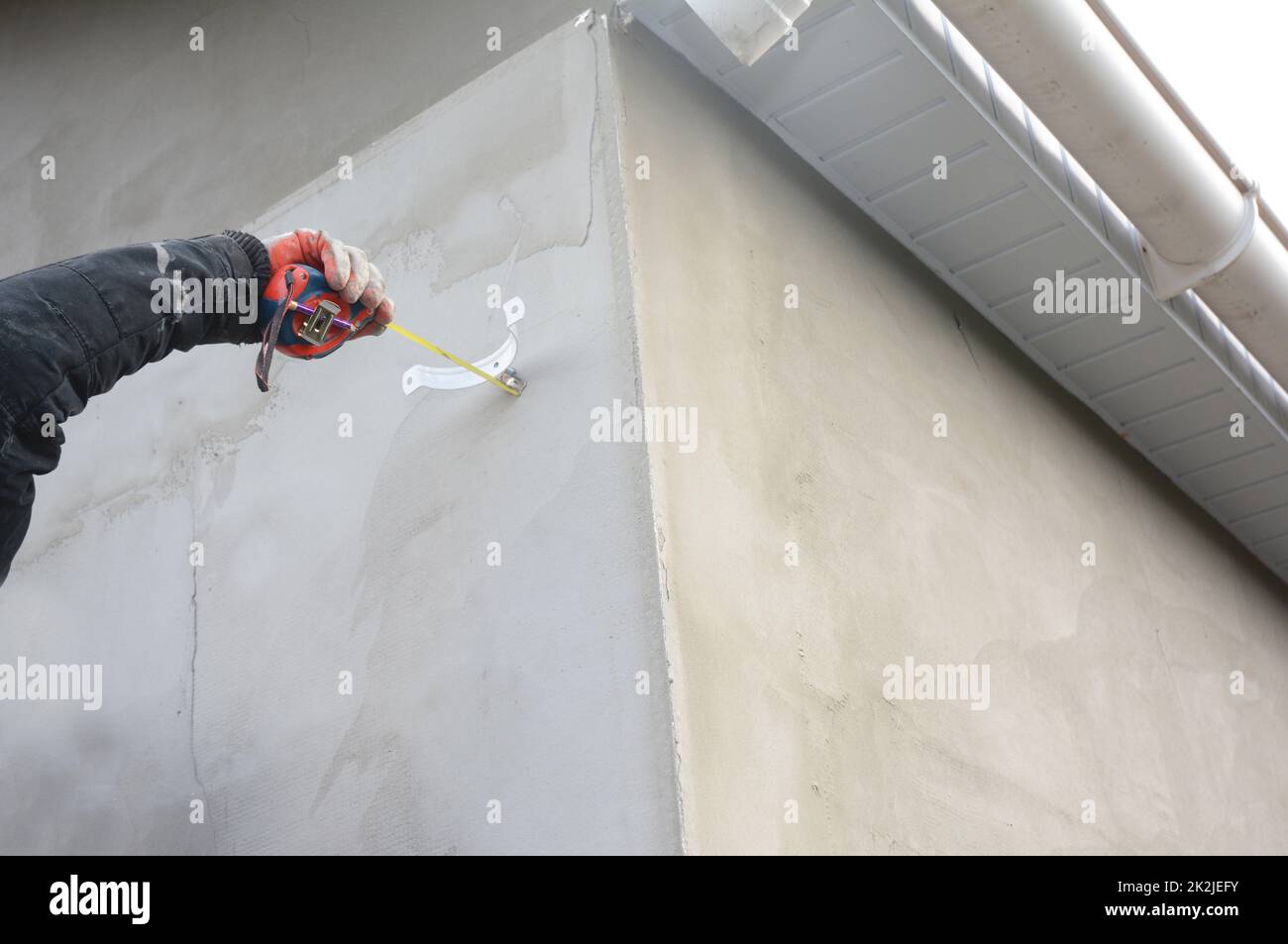 Contractor installing holder for roof gutter downspout pipe Stock Photo