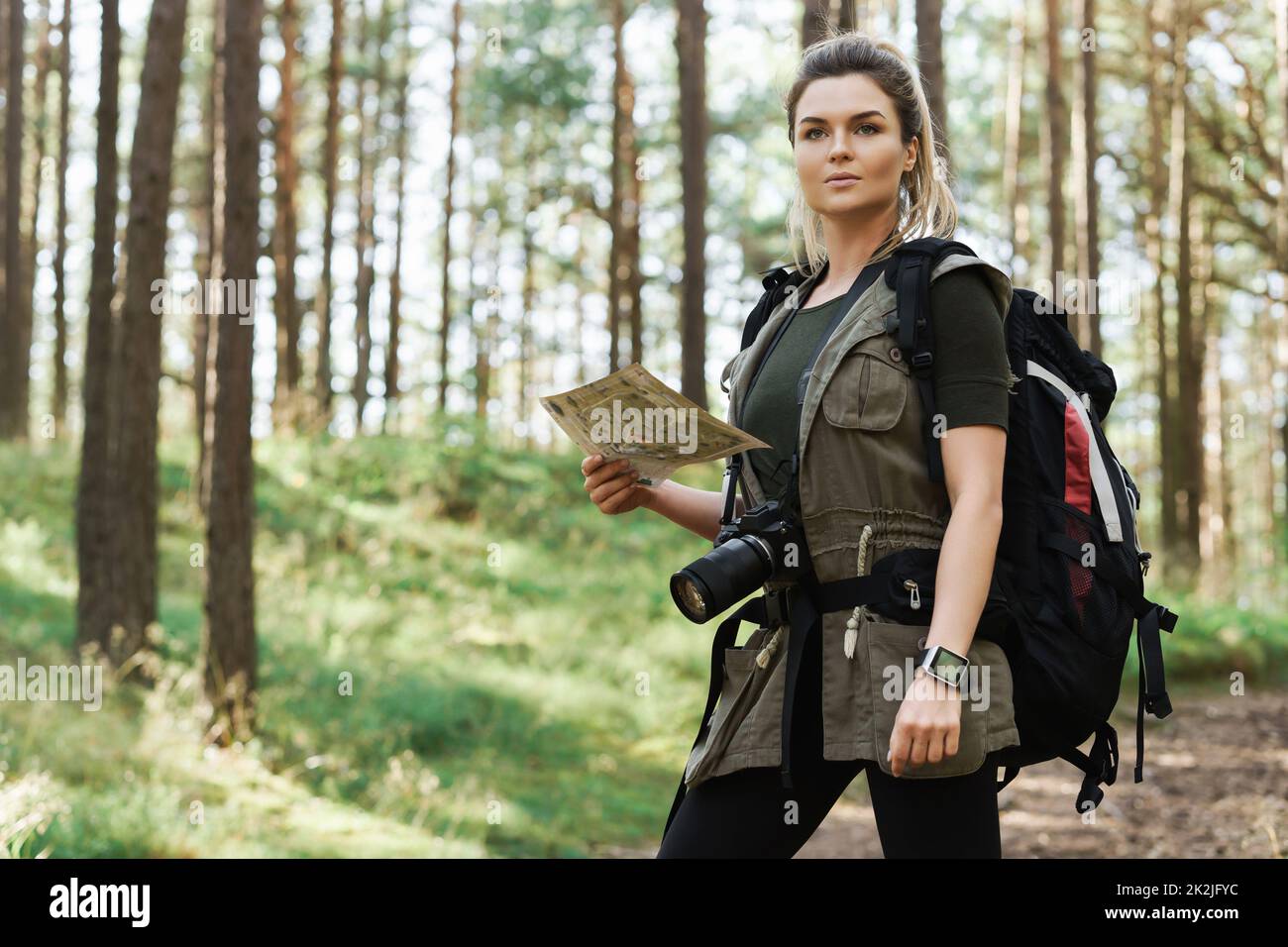 Female hiker with big backpack using map for orienteering in the forest Stock Photo