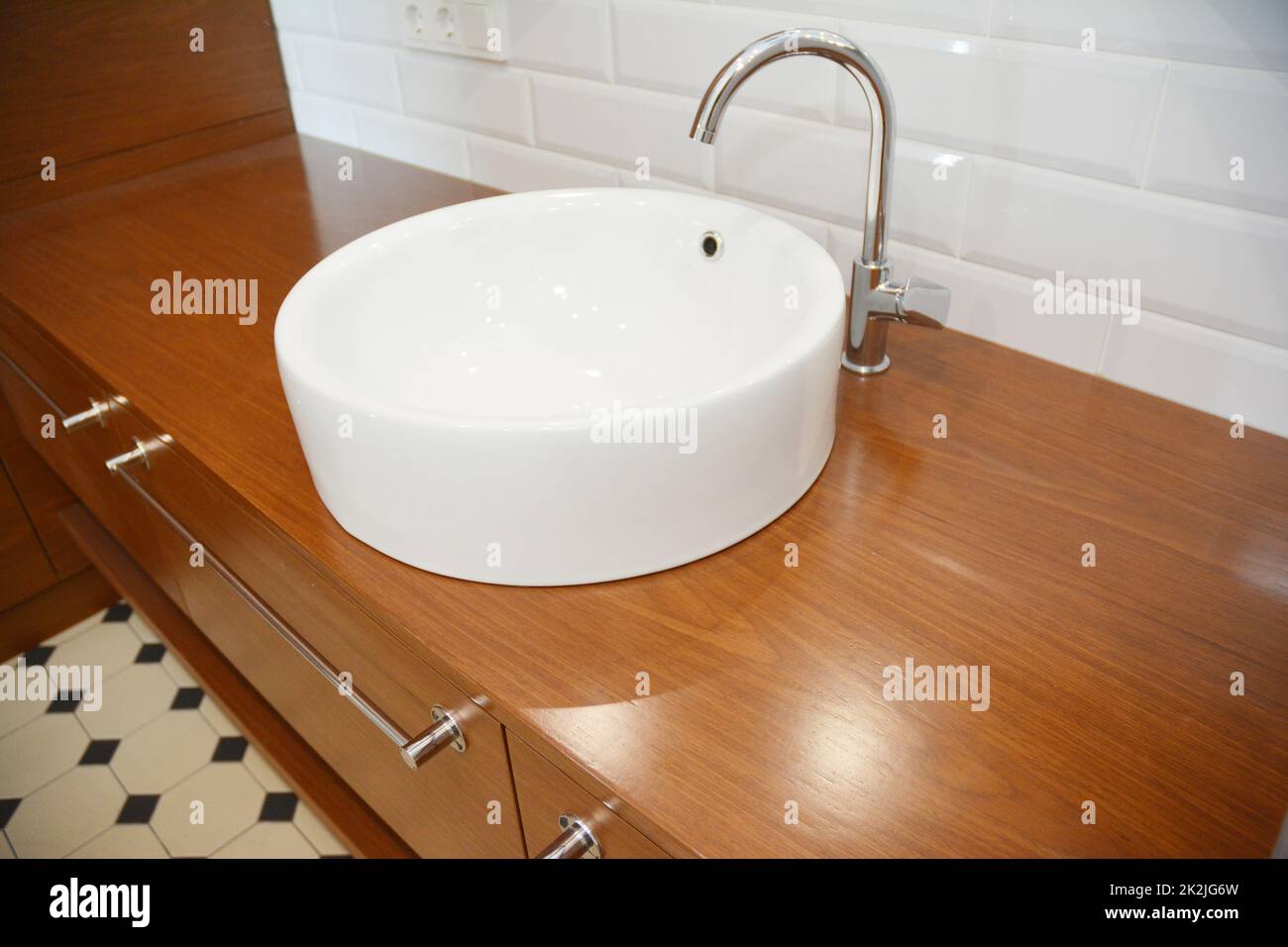 Bathroom ceramic sink with chome water tap and wooden table. Stock Photo