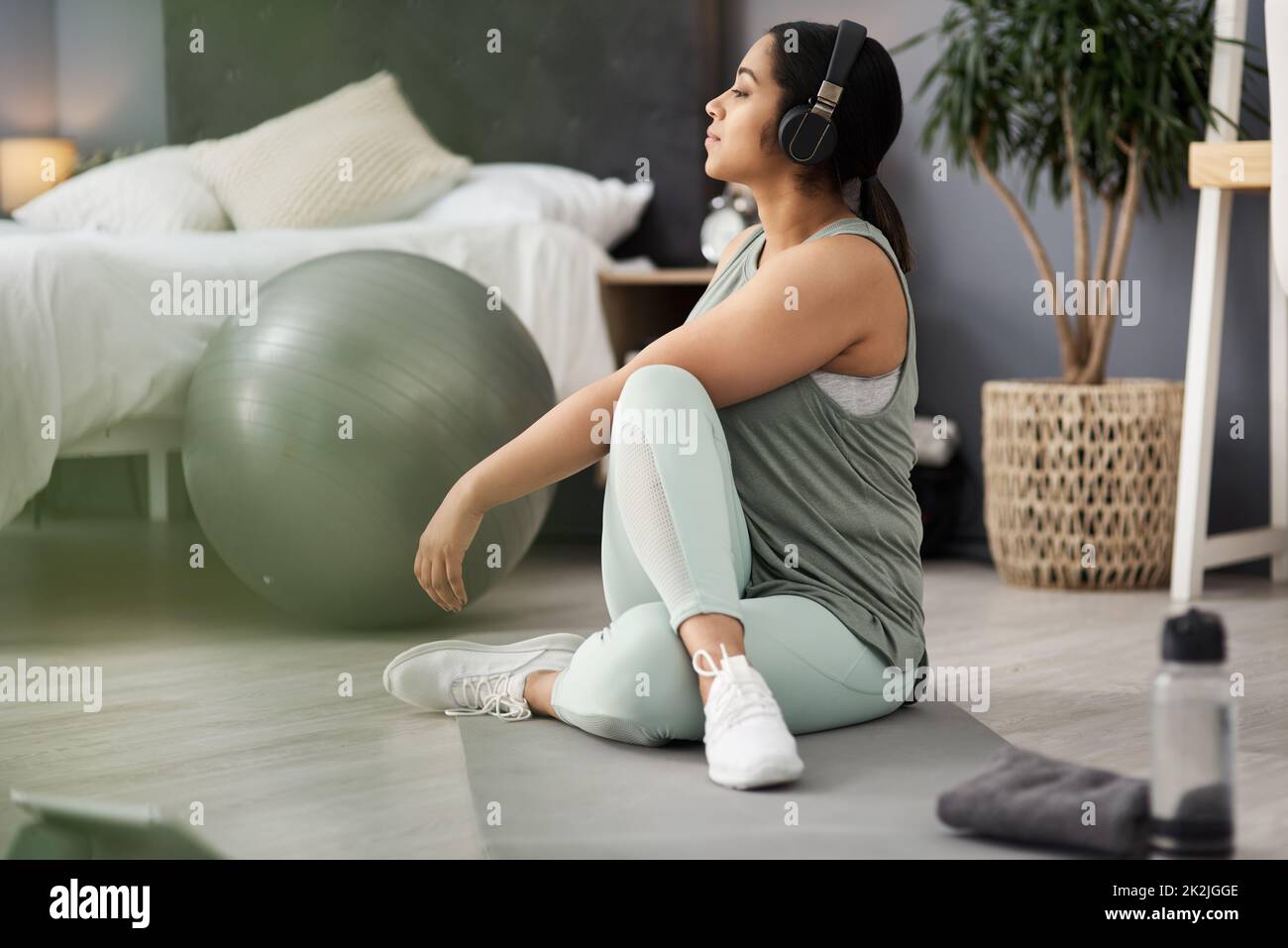 Each day is a new chance to change your life. Shot of a sporty young woman listening to music while exercising at home. Stock Photo