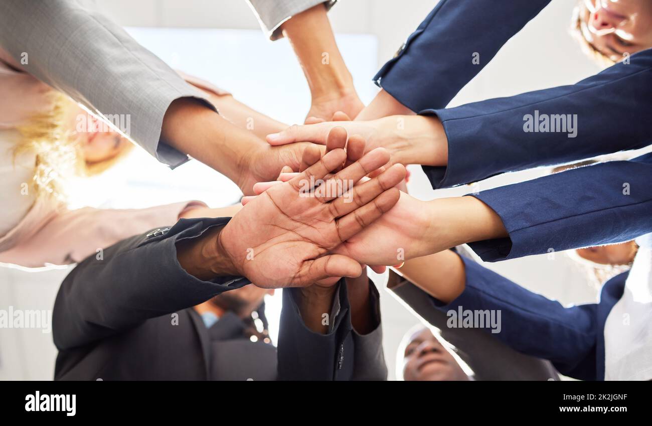 Heres to us reaching our goals. Shot of a group of coworkers huddling their hands together in team sprit. Stock Photo