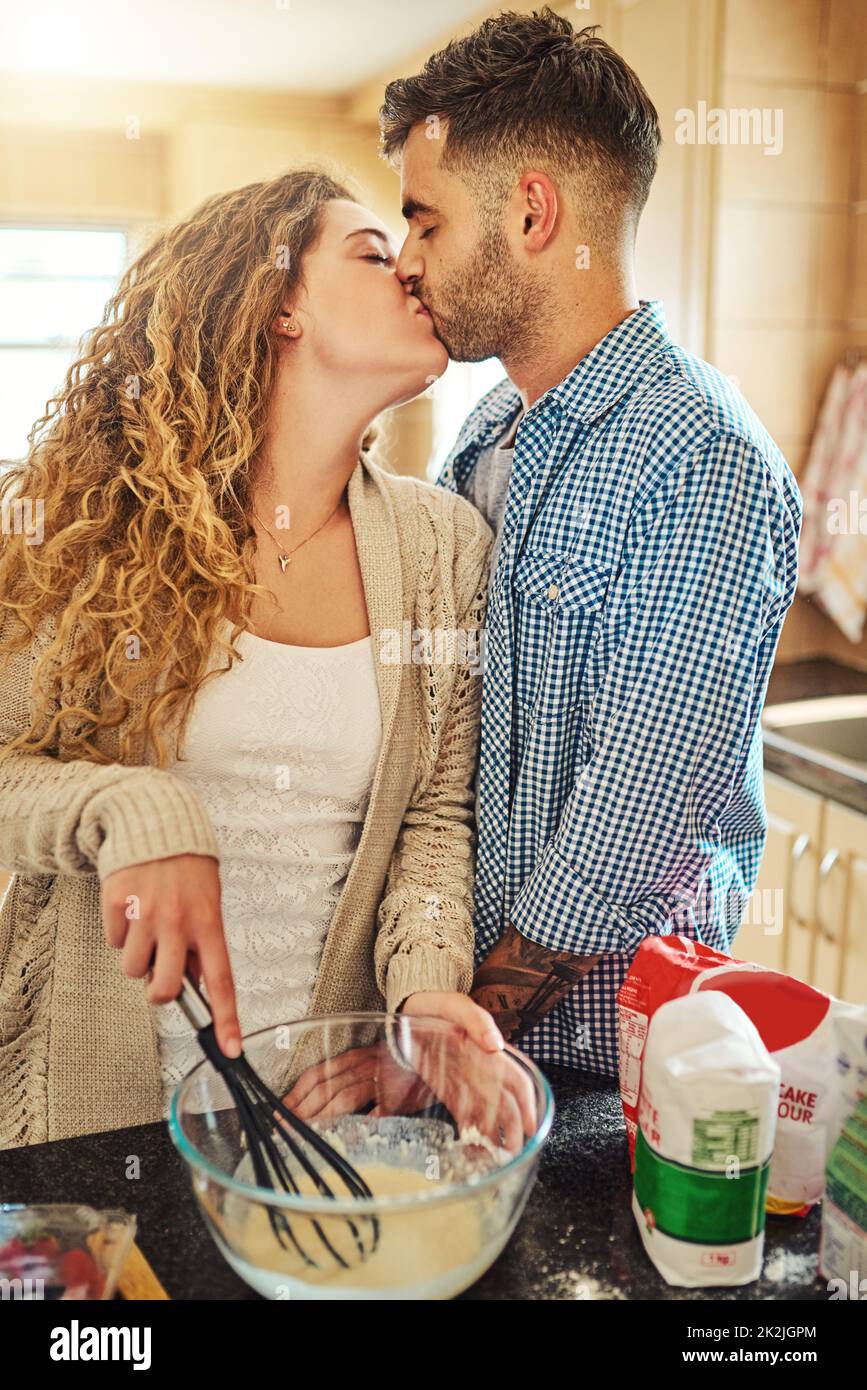 The recipe says one passionate kiss. Shot of a loving couple baking in their kitchen. Stock Photo