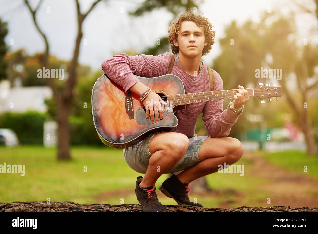 Can I play you a little tune. Portrait of a young man playing guitar outside. Stock Photo