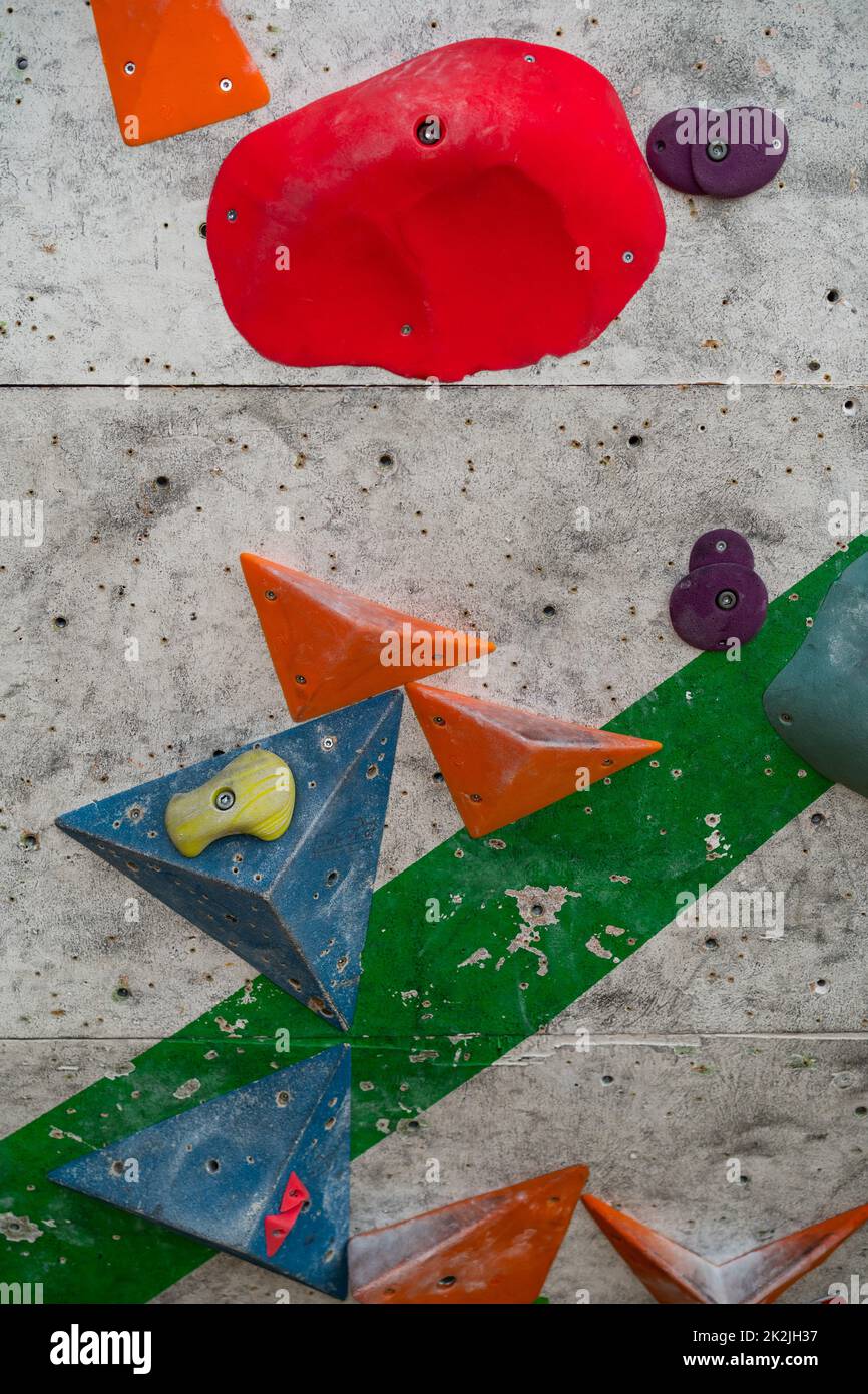 Close up photo of a rock climbing wall with climbing holds in gym. Stock Photo