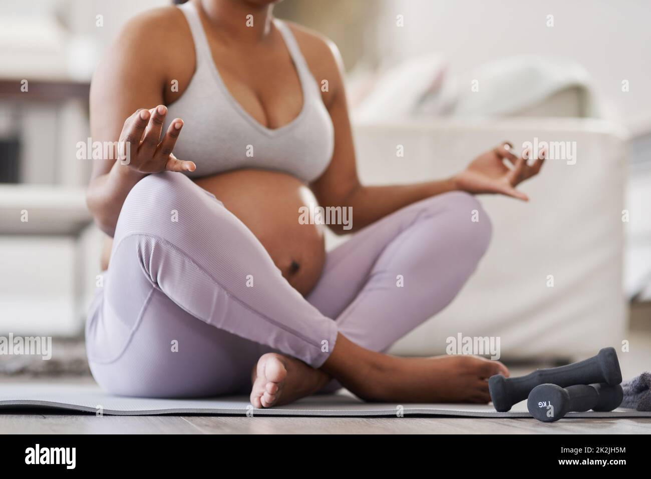 A calm momma= A peaceful baby. Cropped shot of a pregnant woman doing yoga at home. Stock Photo