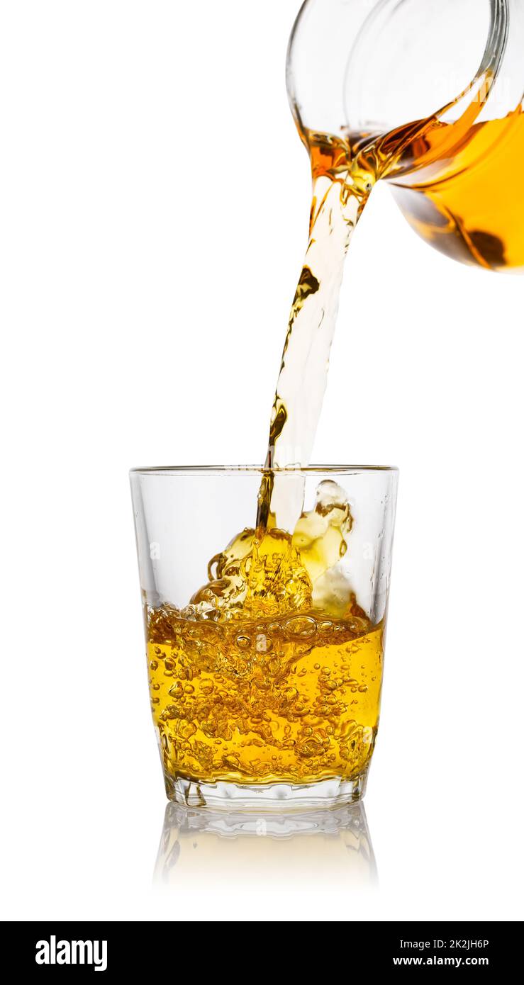 Apple juice pours from the decanter into transparent glass Stock Photo