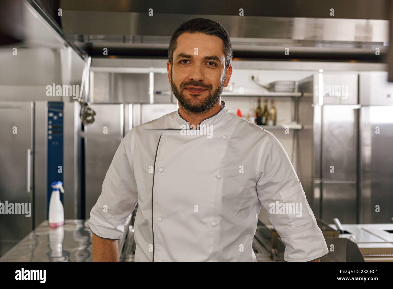 Portrait of handsome male chef in uniform standing on kitchen of restaurant Stock Photo