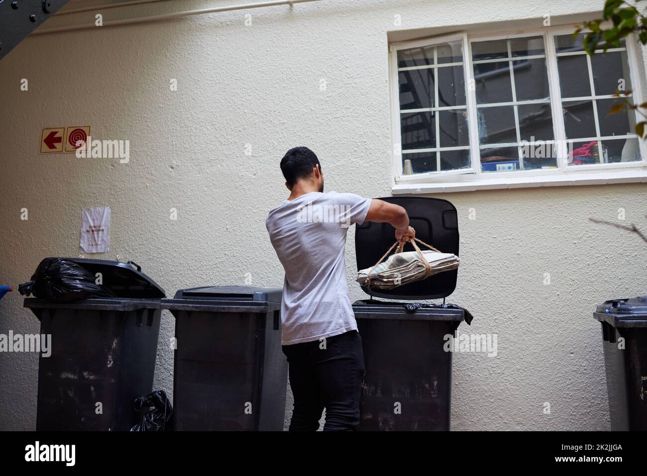 Doing the responsible thing. Shot of a young man putting newspaper in