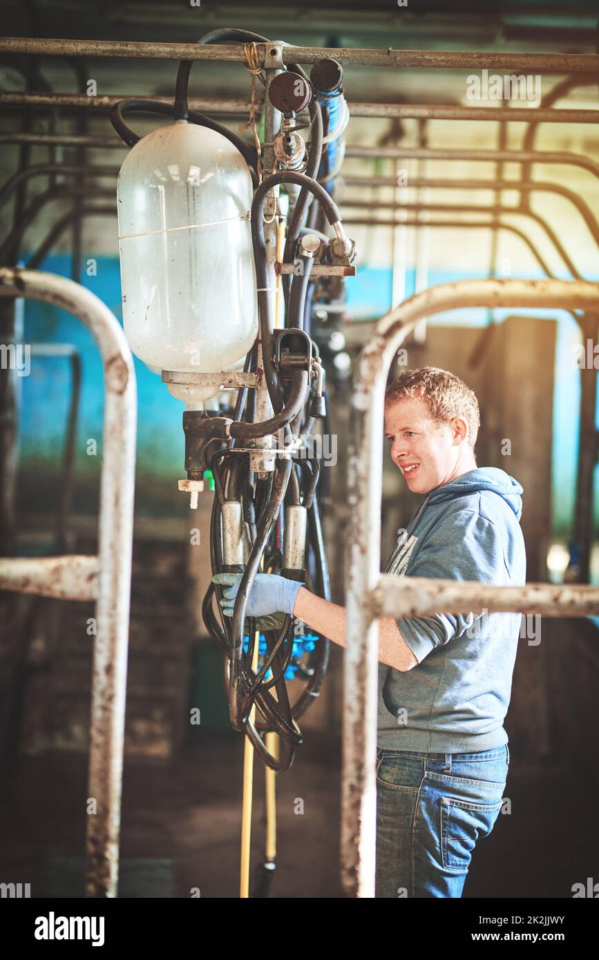 Lets get ready to milk. Shot of a farmer preparing the cow milking equipment on a dairy farm. Stock Photo