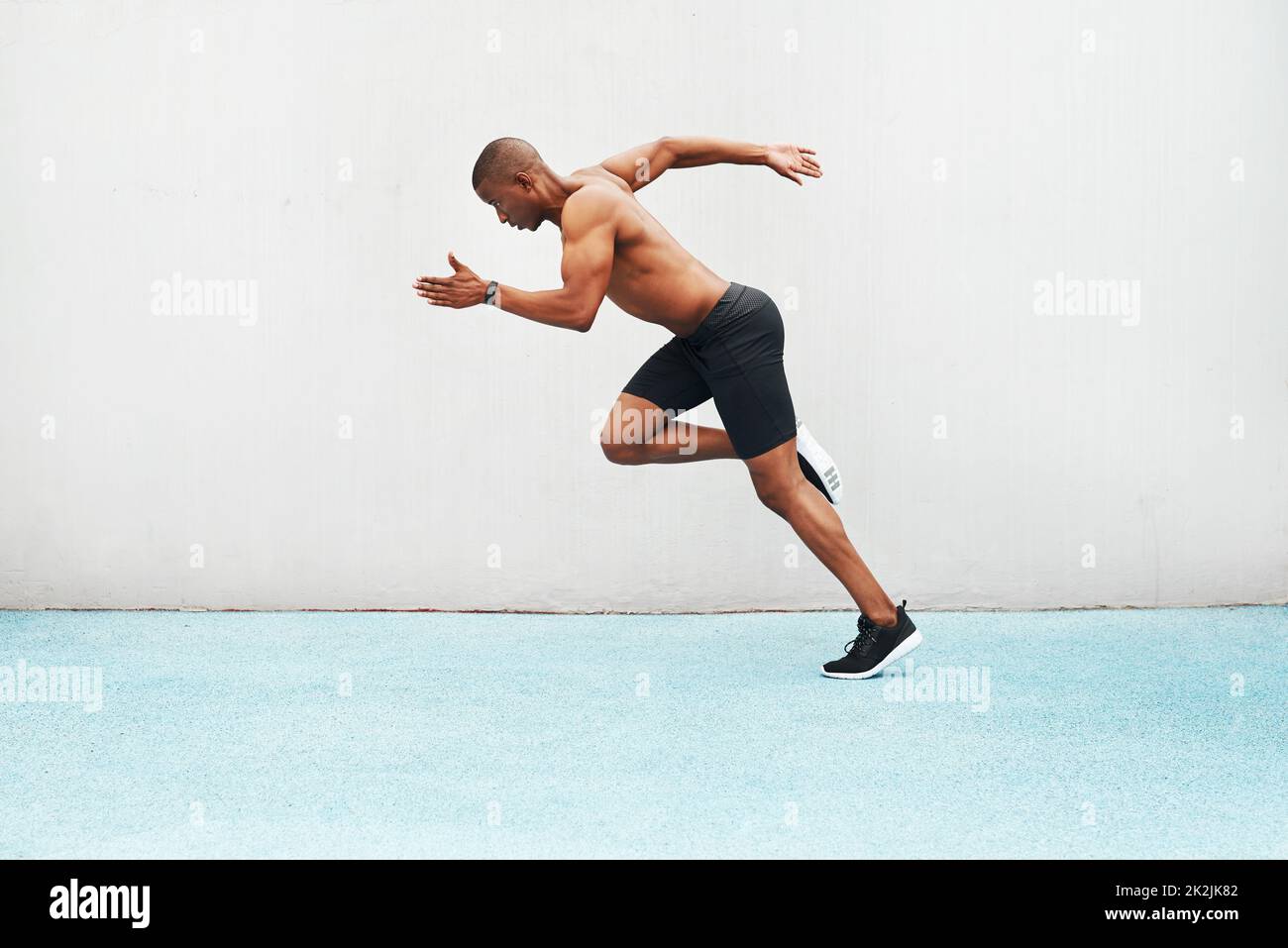 I know every mile will be worth my while. Full length shot of a handsome young athlete running a track field alone during an outdoor workout session. Stock Photo