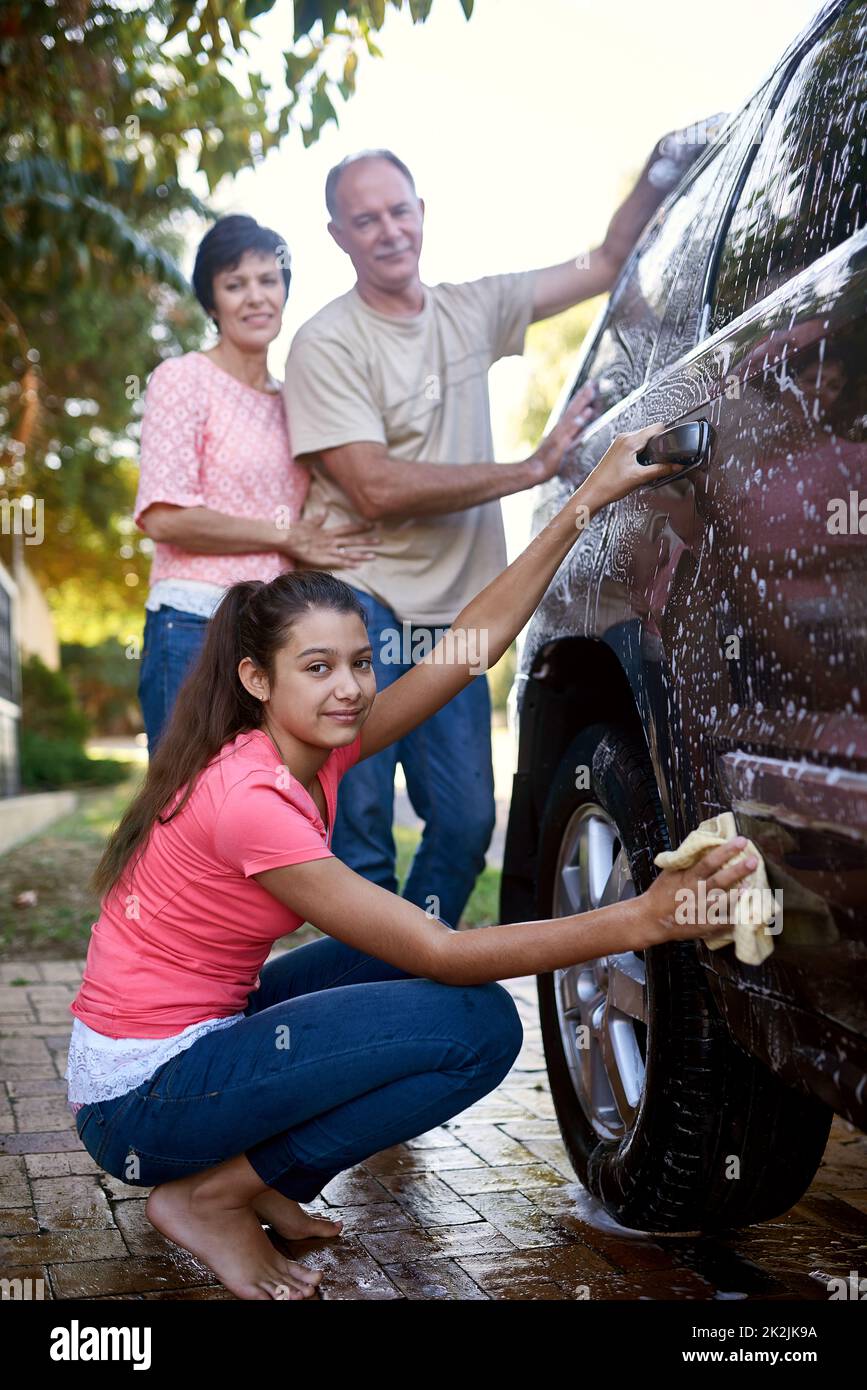 Tackling chores together. Portrait of a family washing a car together outside. Stock Photo